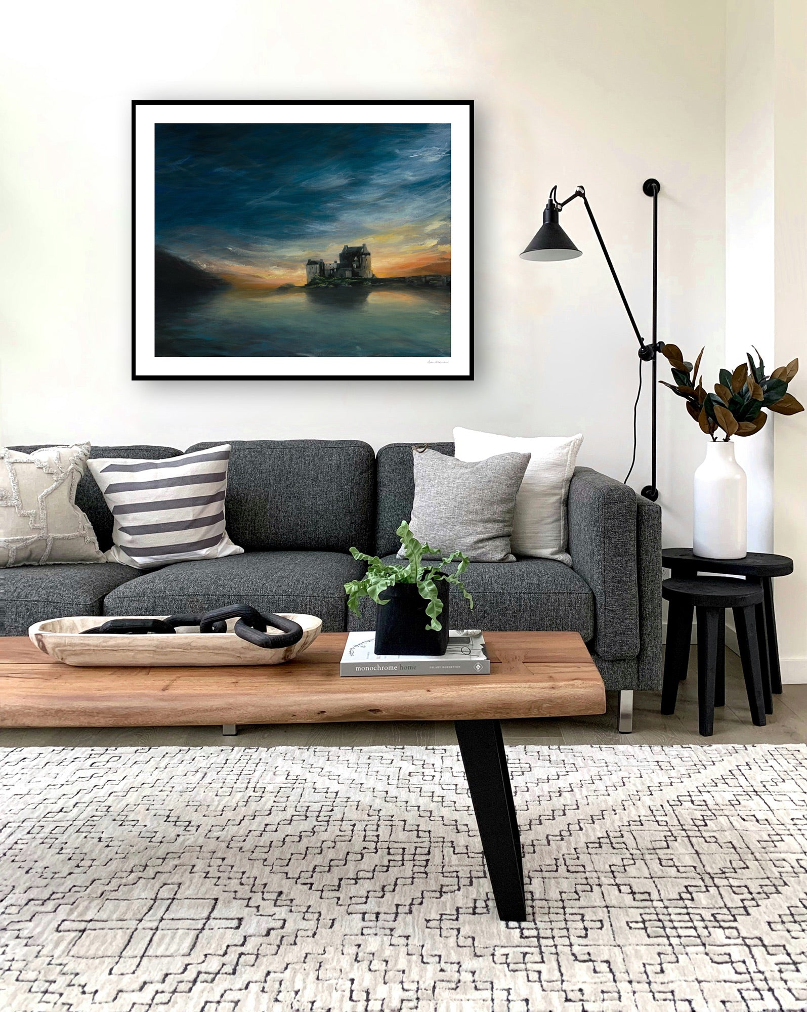 Modern living room with a gray sofa, wooden coffee table, and framed artwork on the wall.