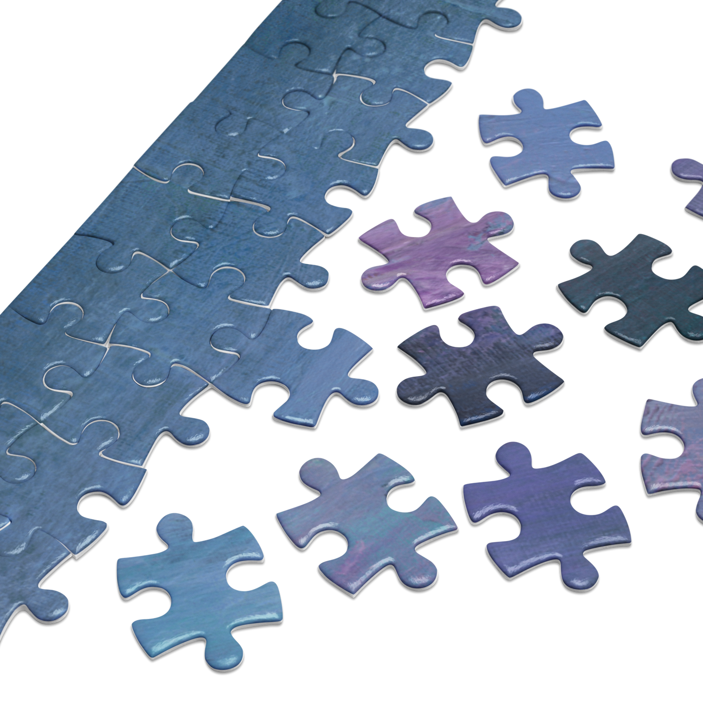 A close-up of a jigsaw puzzle with several loose puzzle pieces scattered on a white background. The puzzle and pieces show a mottled blue, purple, and gray pattern.