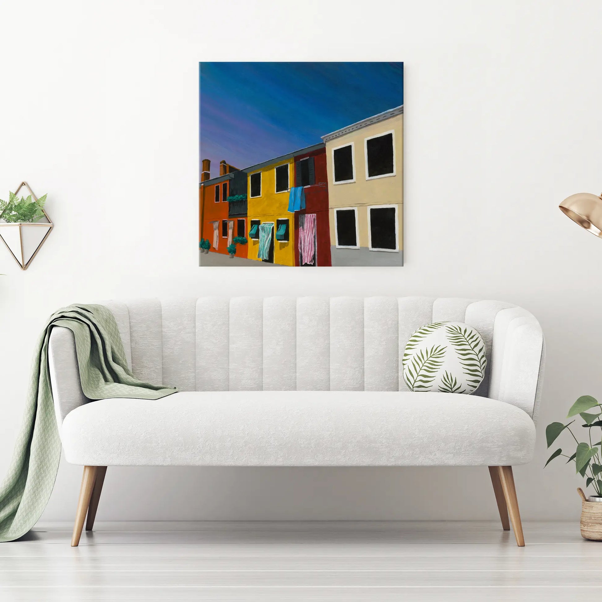 White sofa with a colorful wall art piece above it in a minimalistic living room.