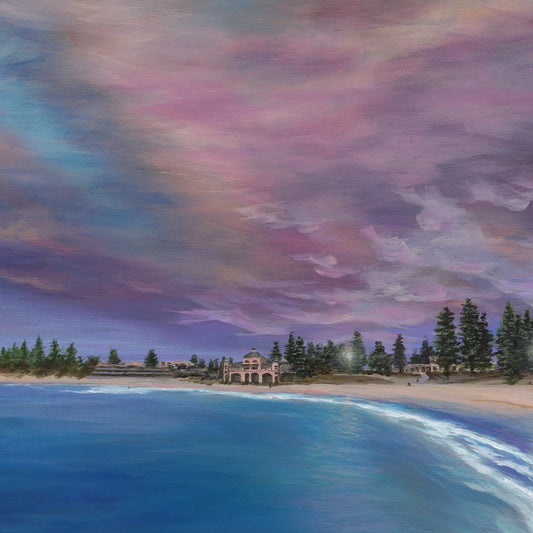 Beach scene with colorful sky and buildings in the distance