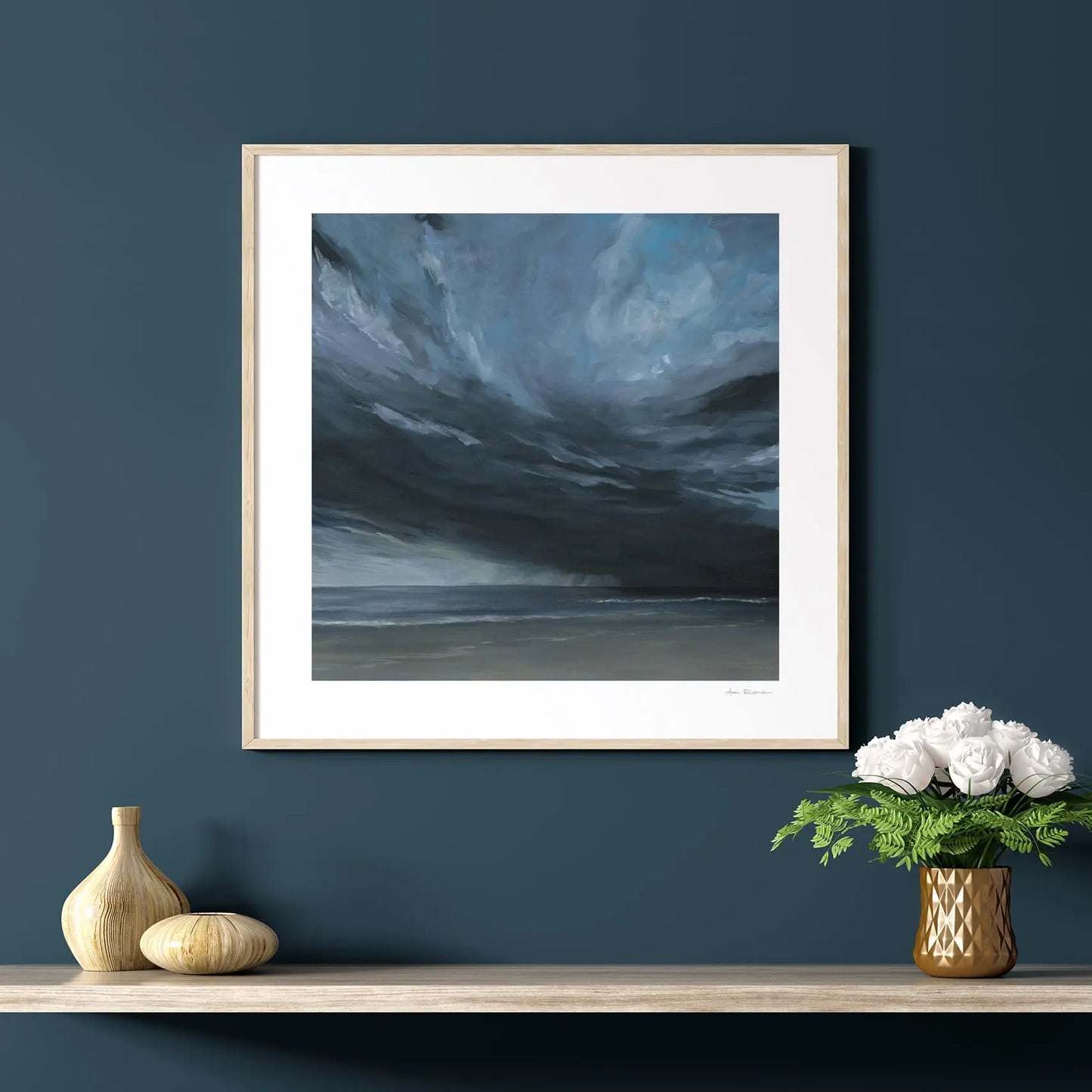 Framed artwork of swirling clouds on a dark blue wall with decorative items below.