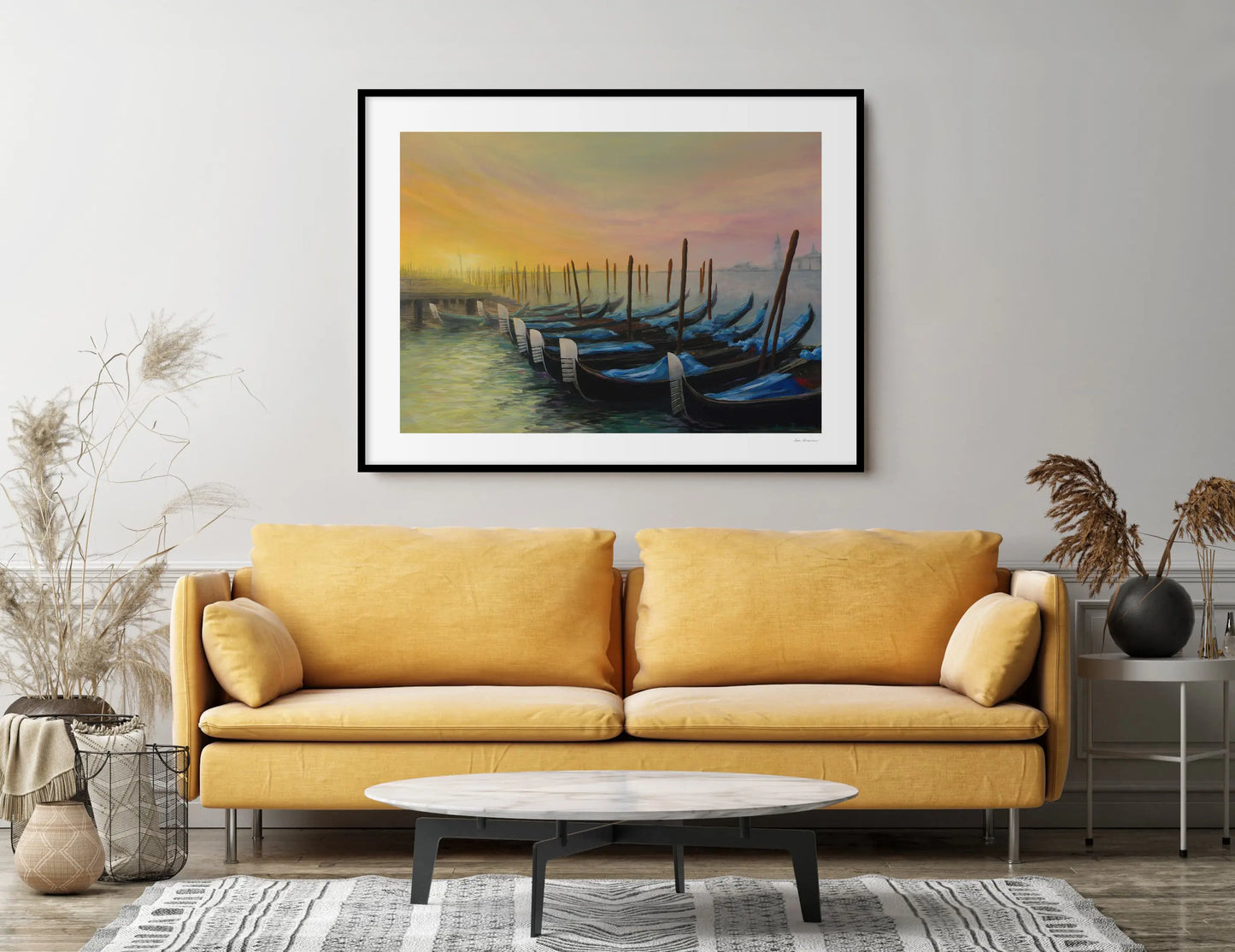 Yellow sofa in a living room with a framed painting of boats on the wall.