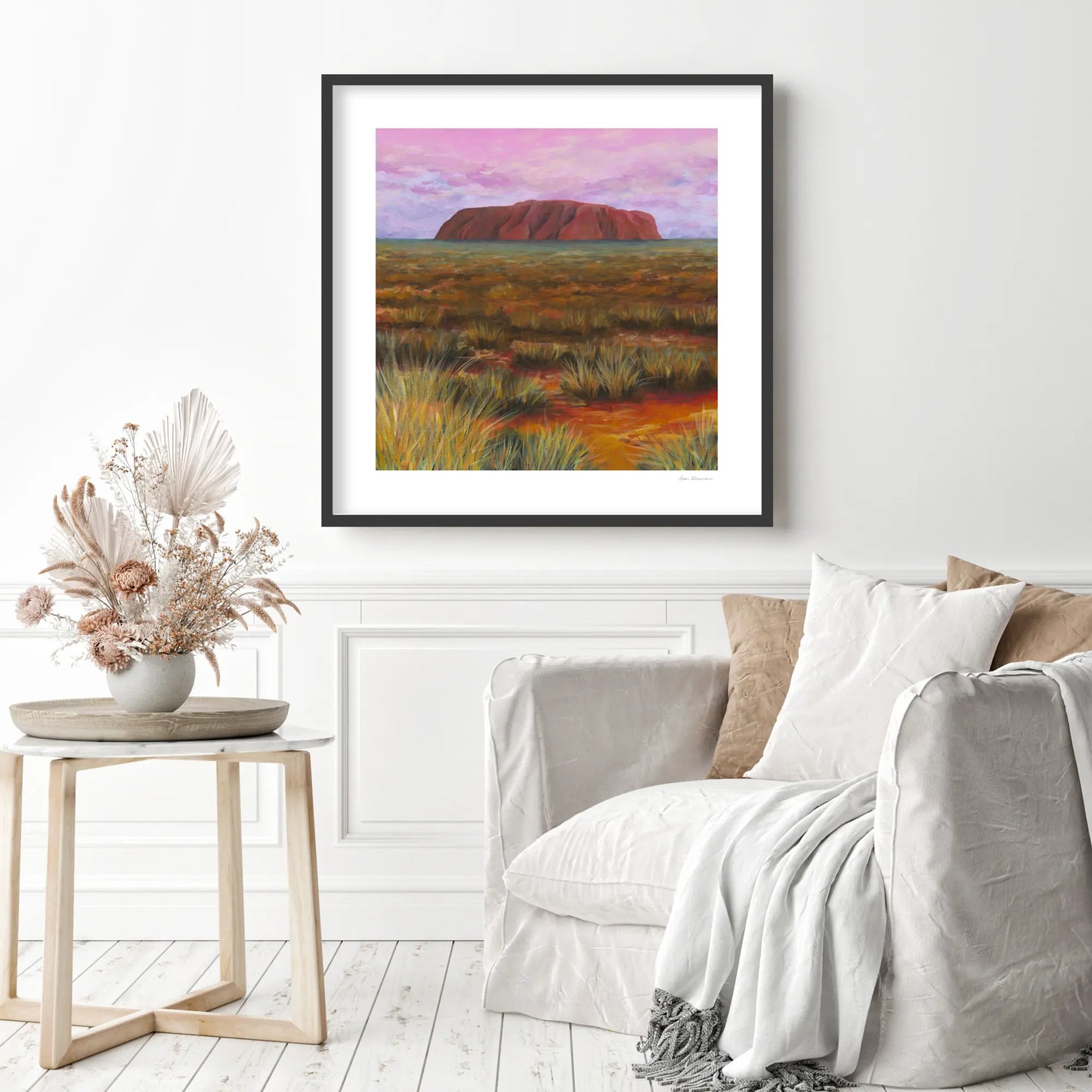 Framed artwork of Uluru in a desert landscape above a sofa in a living room.