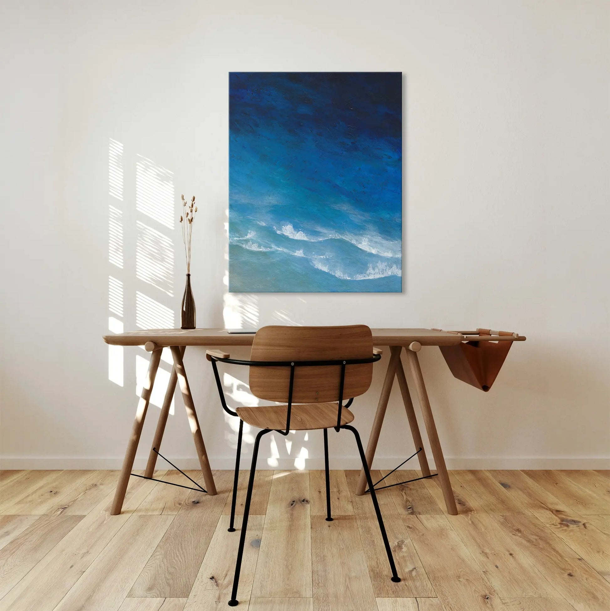 Wooden desk with chair in a room with a blue abstract painting on the wall.