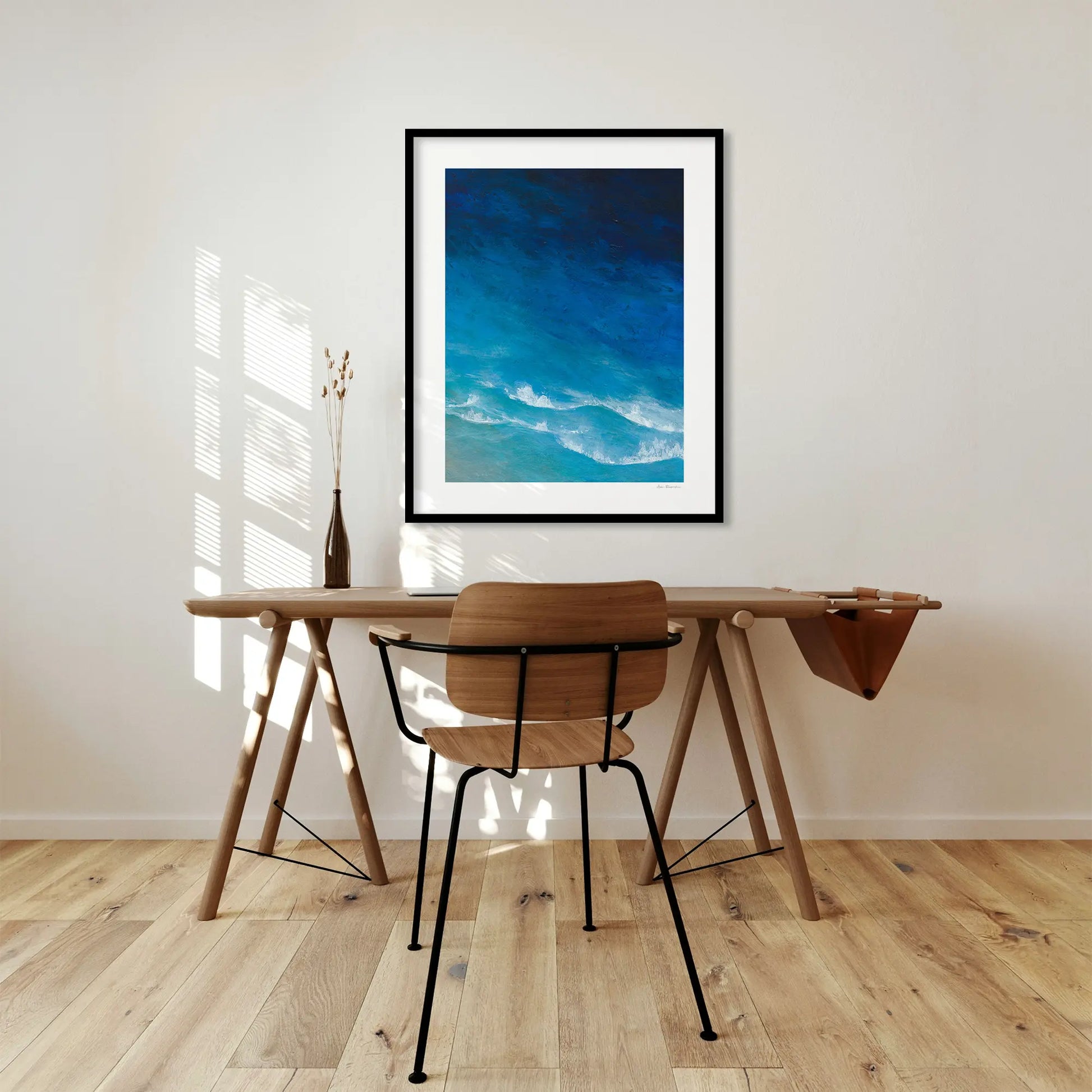Wooden desk with chair in a room with a framed blue artwork on the wall.