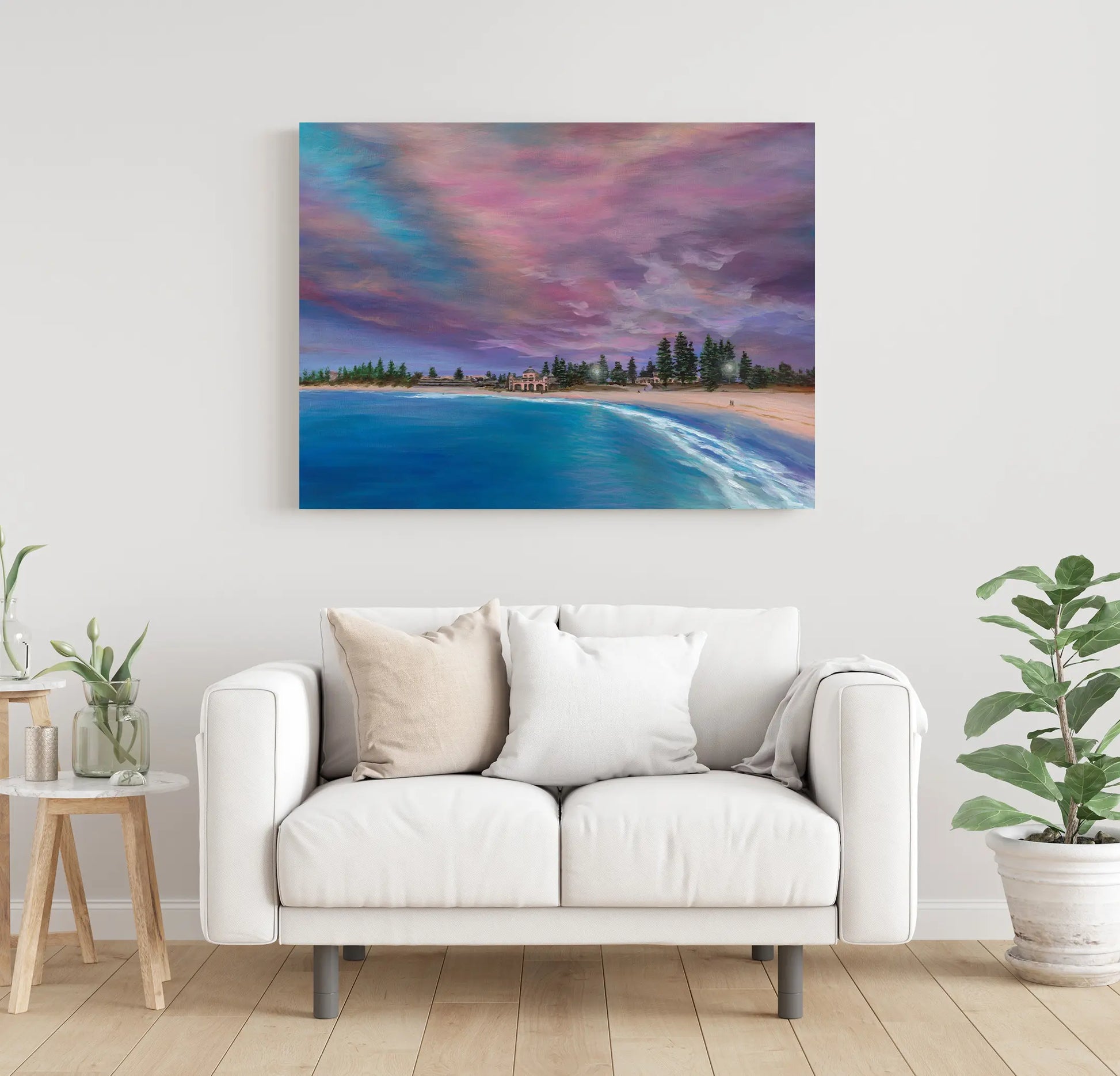 Living room with a white sofa, side table, and a large painting of a beach scene on the wall.