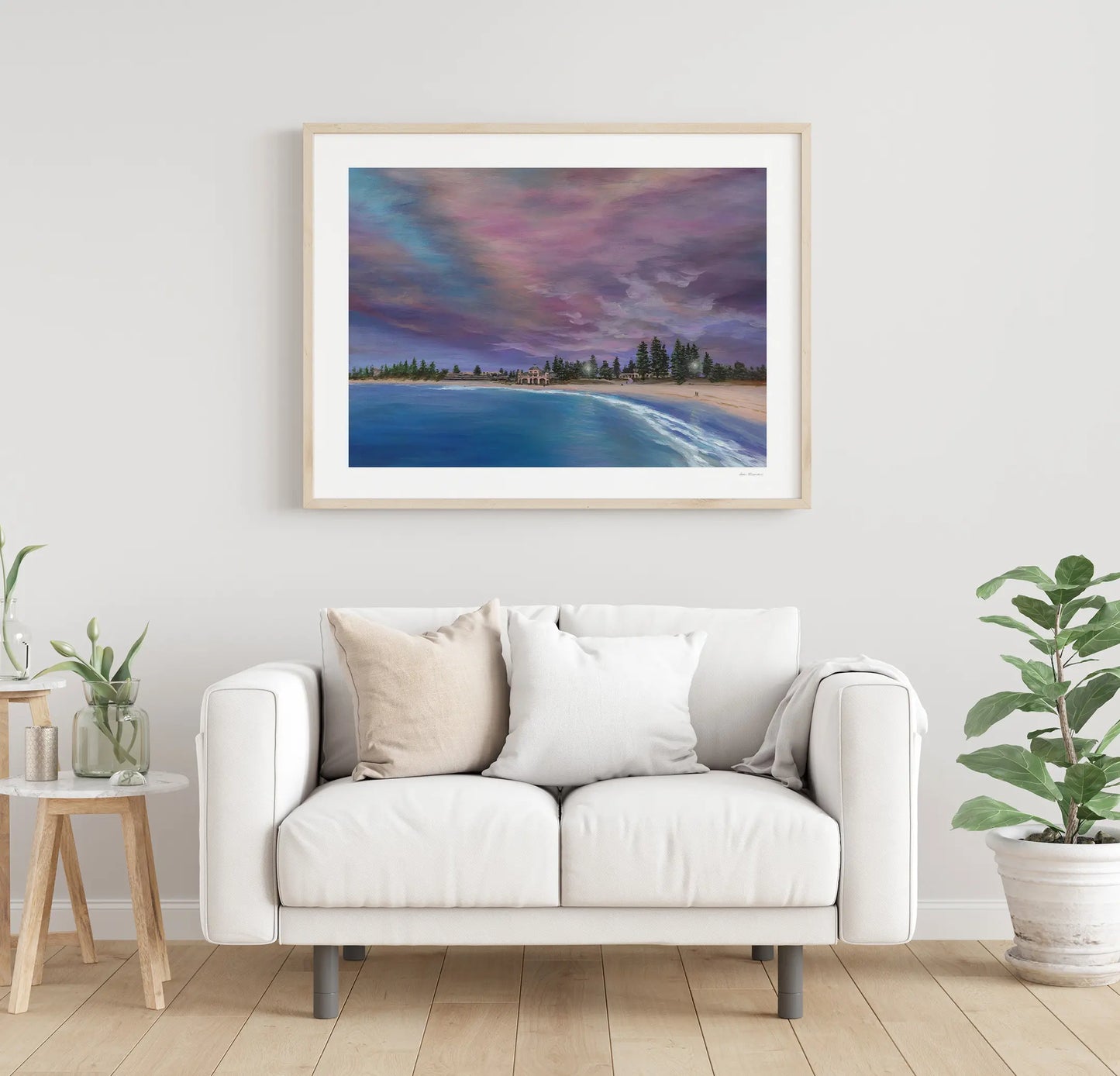 Framed artwork of a beach scene above a white sofa in a living room.