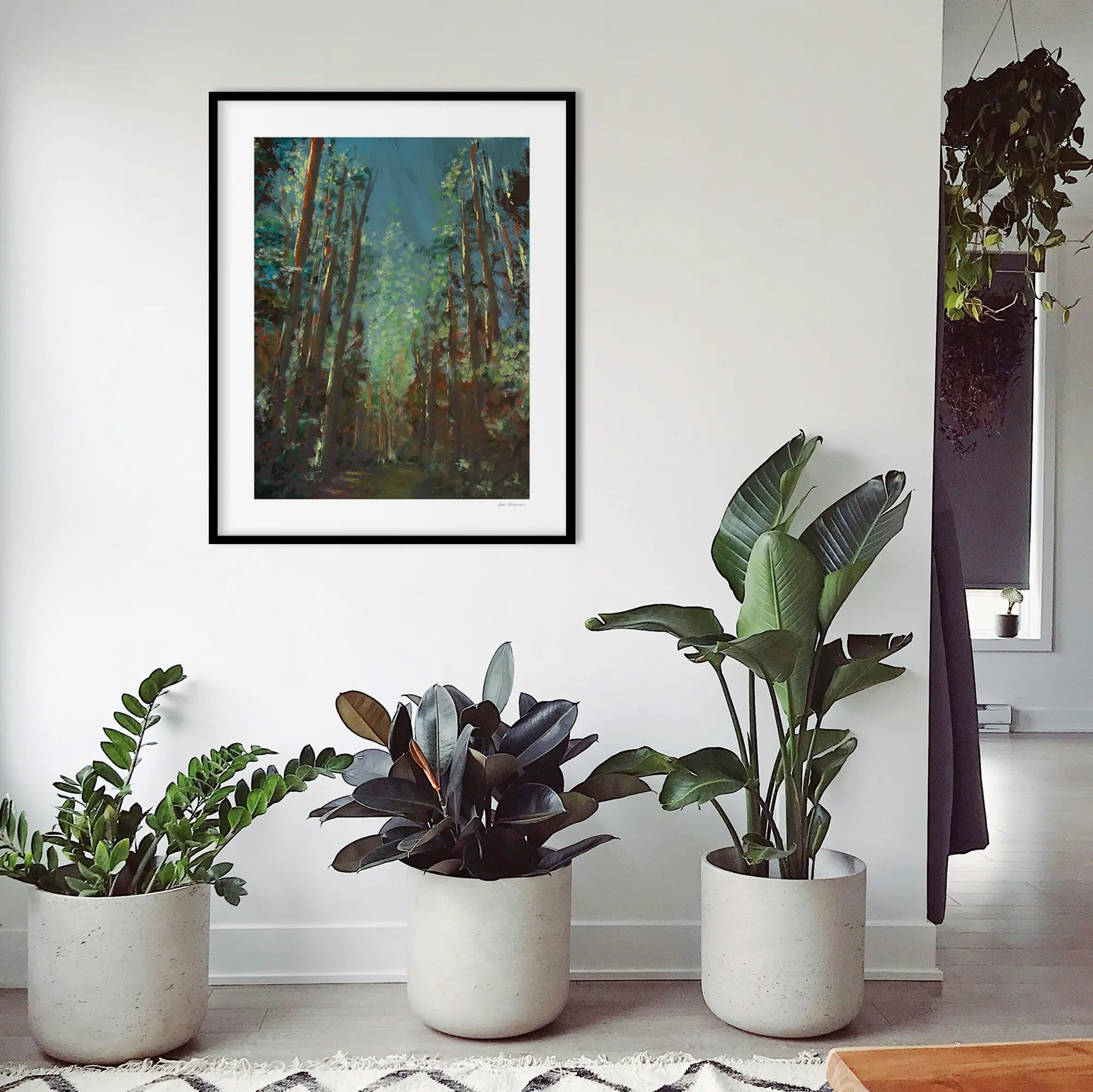Three potted plants with a framed painting of a forest above them.