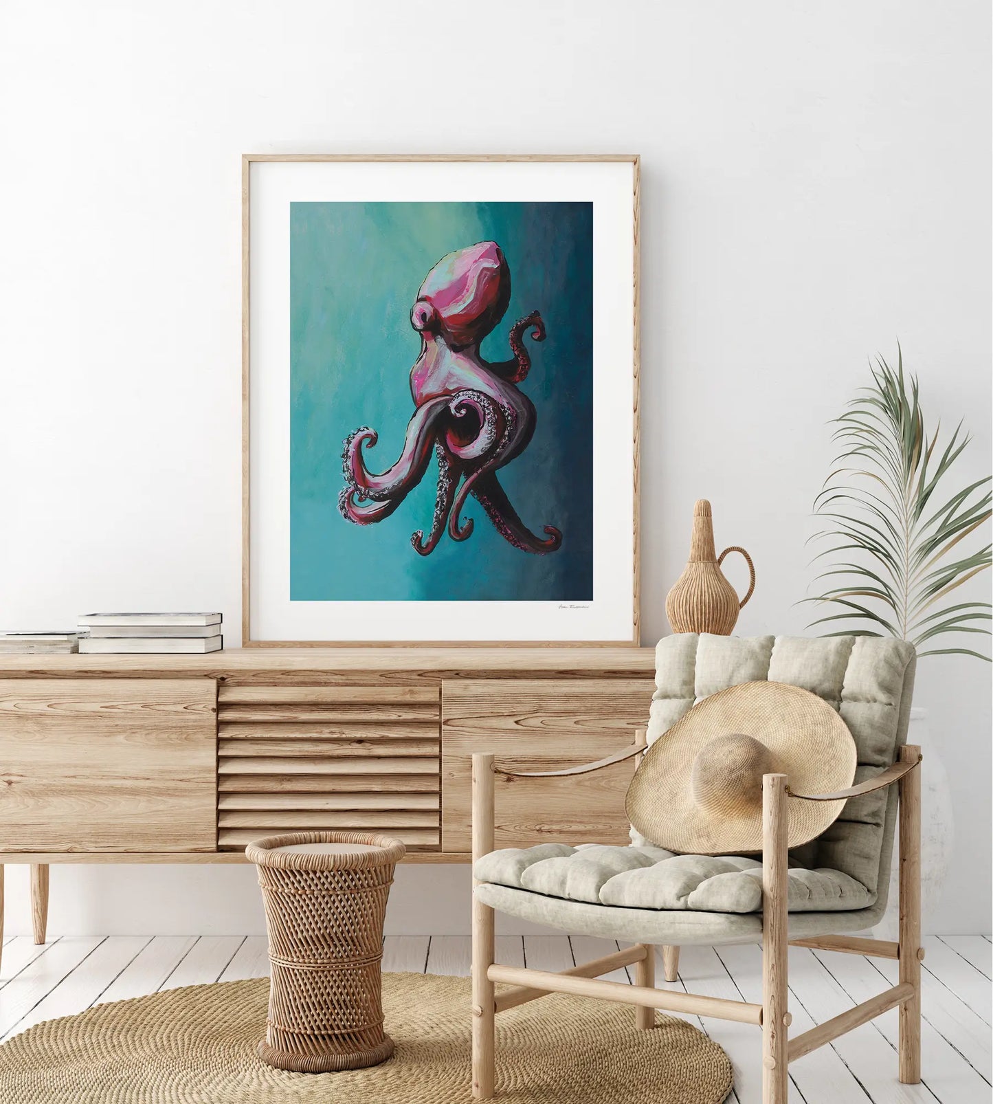Framed artwork of an octopus on a wall above a wooden cabinet with a chair and decorative items.