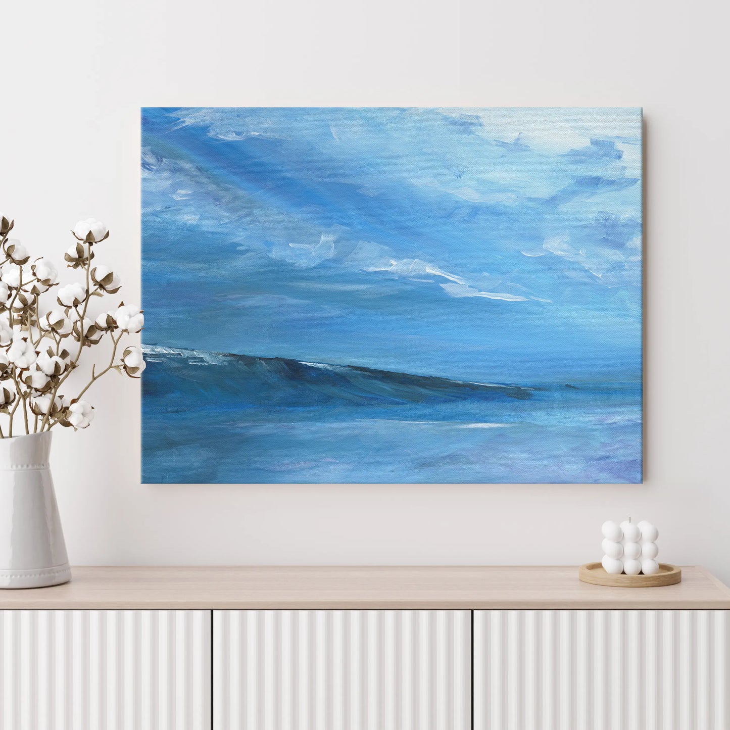 Abstract blue painting on a wall above a wooden shelf with decorative items.